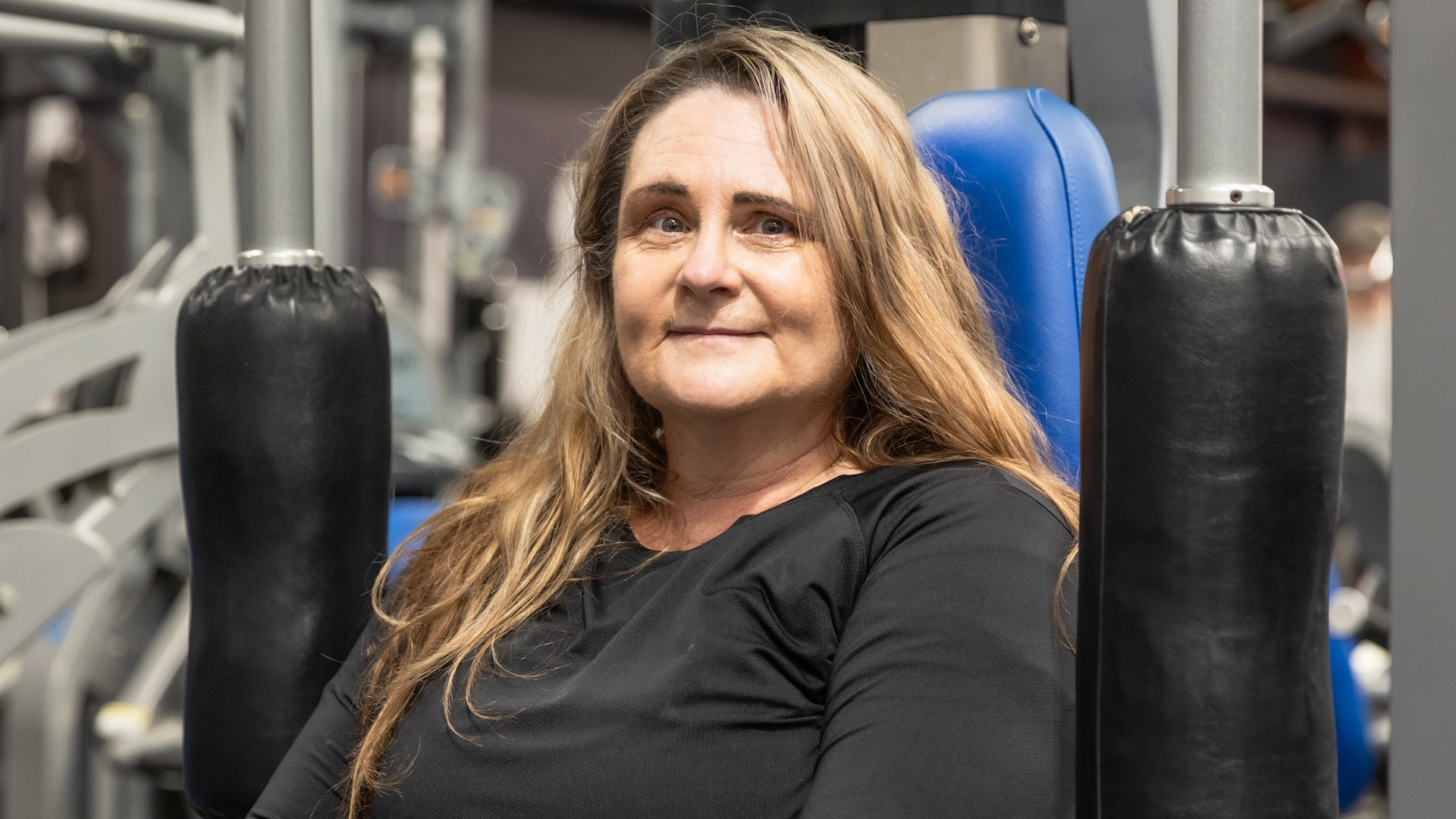 Kelly, a member of Genesis Ballarat, uses a chest press machine in the gym. After recovering from a serious motorbike accident, Kelly has been working hard to rebuild her strength and regain confidence, supported by the gym's facilities and community.