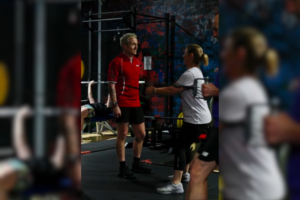 In a vibrant gym setting at Genesis Ballarat, a man in a red shirt engages with a woman in a white shirt during a workout session.
